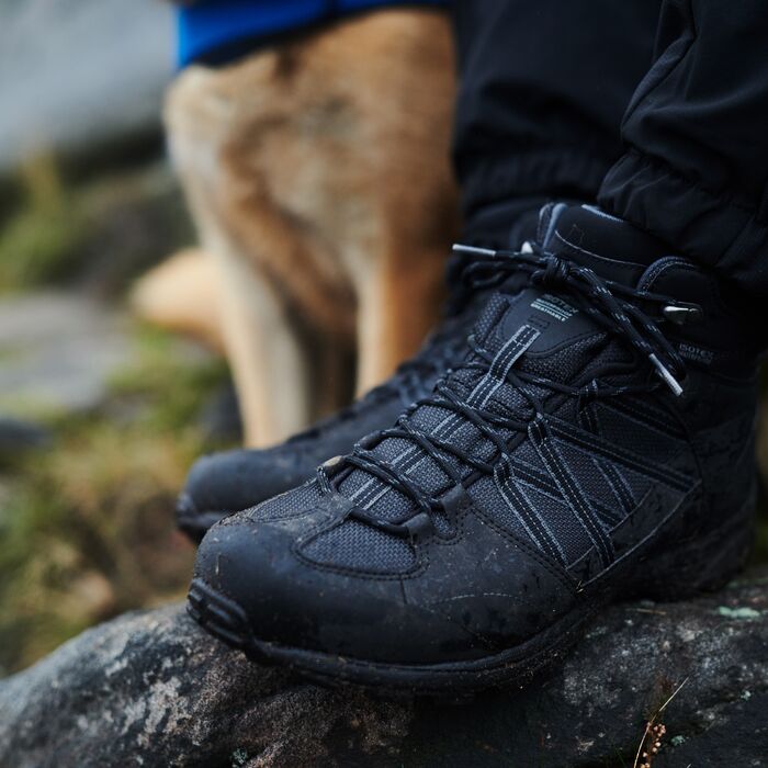 A pair of black walking boots with mud on them.